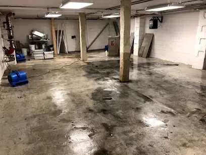 Air mover blowing across a wet concrete basement floor