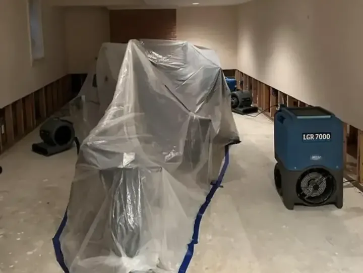 Plastic containment and an LGR dehumidifier drying a room with the lower walls cut open