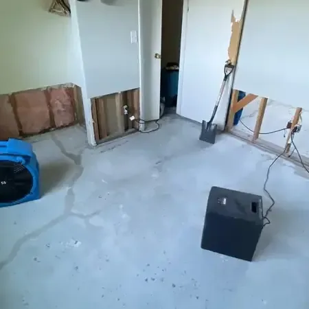 Air movers and a dehumidifier drying a room with lower drywall removed