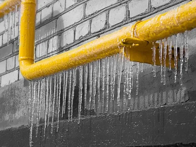 Ice hanging from a frozen pipe along a block foundation wall